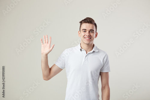 Affable guy dressed in a white t-shirt and jeans is on a white background in the studio