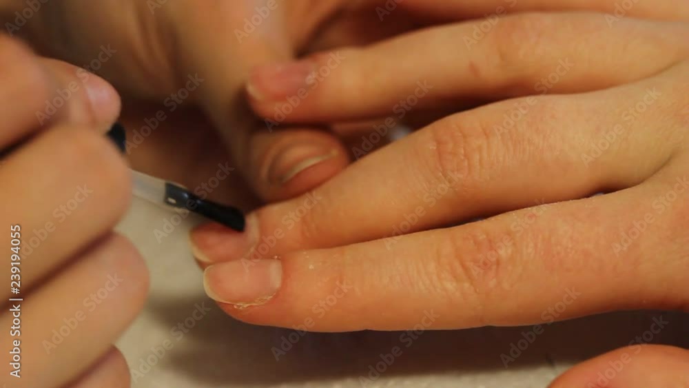 Closeup shot of a beautician applying nail polish to female nail in a nail salon. Close up of a woman hand with pink nailpolish after the manicure. Closeup shot of a beautician applying nail polish to female nail in a nail salon. Close up of a woman hand with pink nailpolish after the manicure.