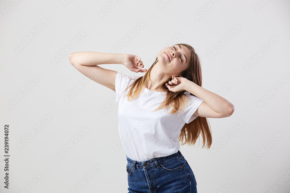 Lazy girl dressed in a white t-shirt and jeans is on a white background in the studio Lazy girl dressed in a white t-shirt and jeans is on a white background in the studio