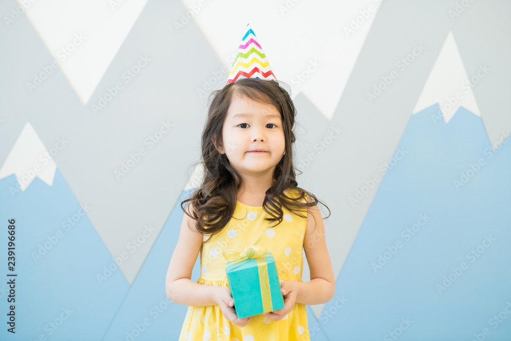 Φωτογραφία Serious beautiful Asian birthday girl with curly hair wearing party hat holding