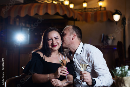 Man and woman on a date in a restaurant holding champagne in their hands