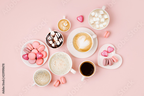 Various kinds of coffee in cups of different size with candys and macaroons on pale pink background. Coffee Time concept. Flat lay, top view