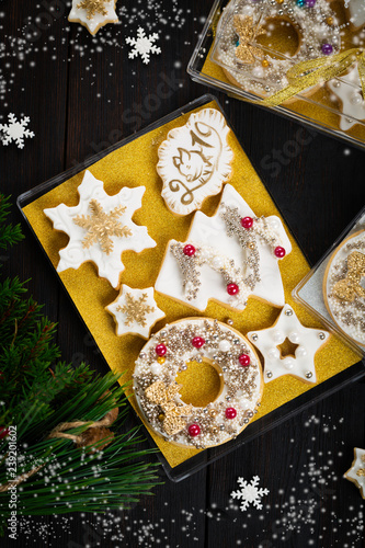 Gingerbread cookies gift set box with white icing  silver and golden sprinkles  snowflake  Christmas tree  stars and pig face on biscuits  dark wooden background  homemade sweets present  copy space 