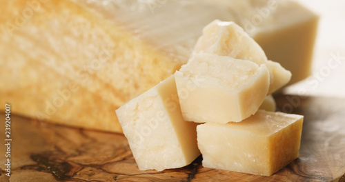 Closeup of hard parmesan cheese cubes on olive cutting board