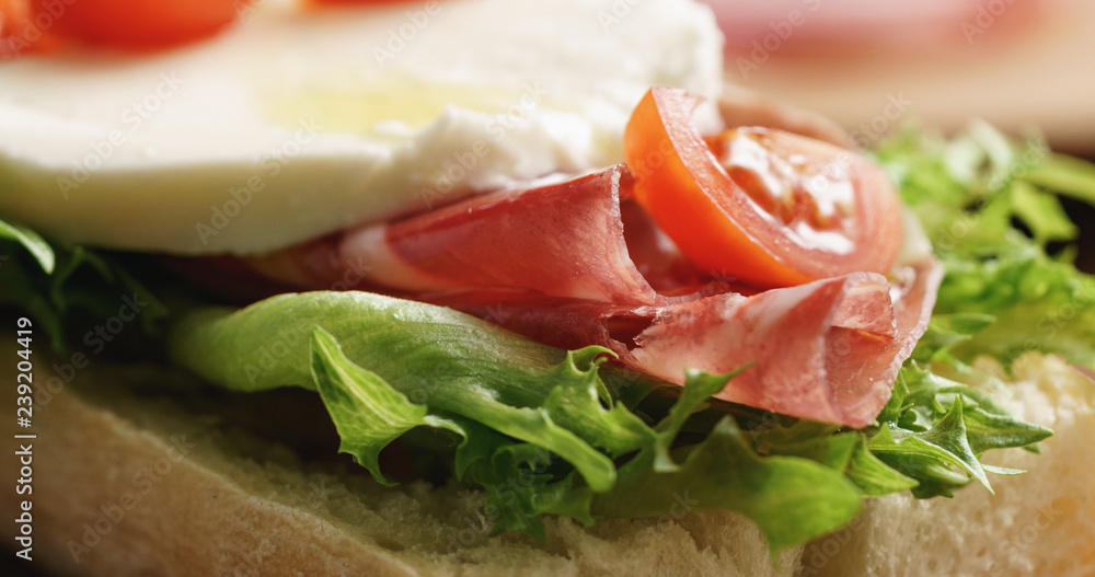 Closeup   of open sandwich with prosciutto, mozzarella and tomatoes on kitchen table
