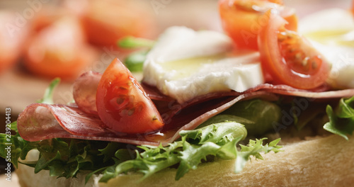 Closeup of open sandwich with prosciutto, mozzarella and tomatoes on kitchen table