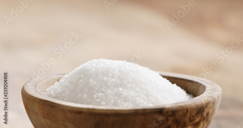Closeup of extra sea salt in wood bowl on wooden table