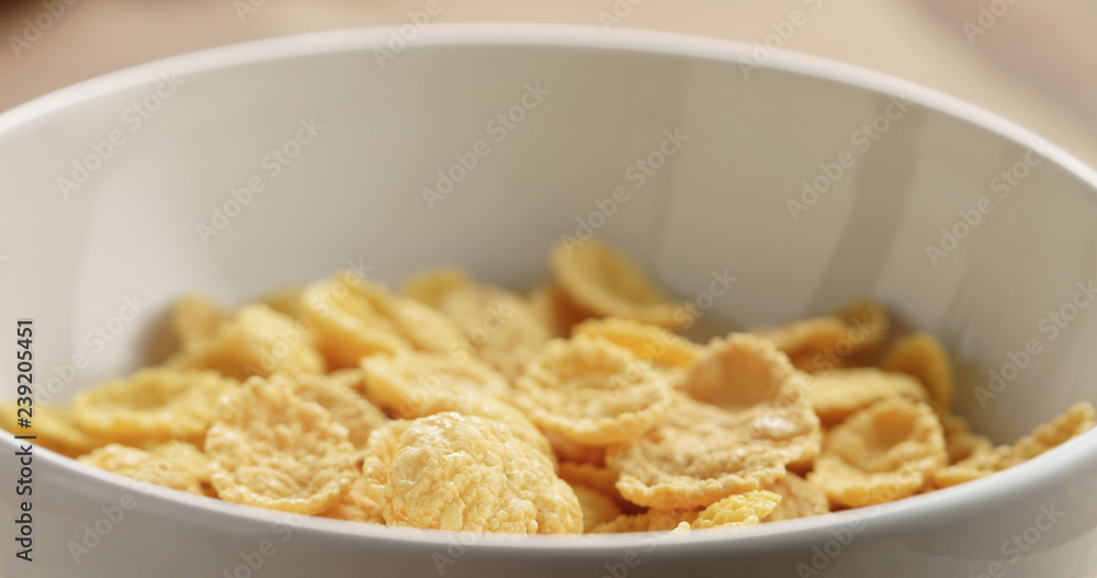 Closeup of dry corn flakes for breakfast in bowl on table Closeup of dry corn flakes for breakfast in bowl on table
