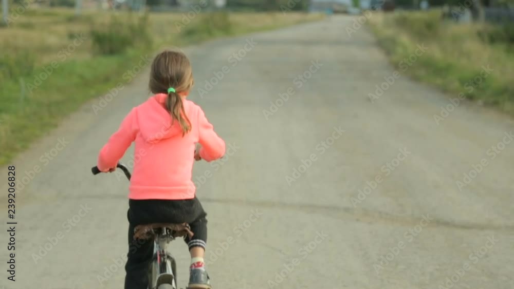 Small girl riding bike along the rural road Small girl riding bike along the rural road