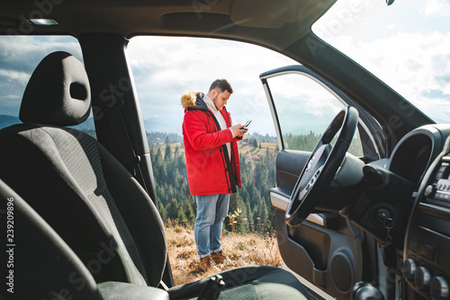 man standing near car with drone controller taking picture. view through car