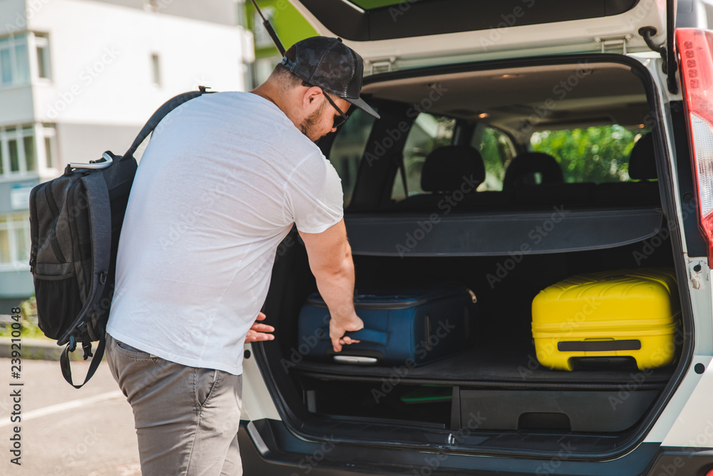 man putting bags in car trunk. ready for car travel man putting bags in car trunk. ready for car travel