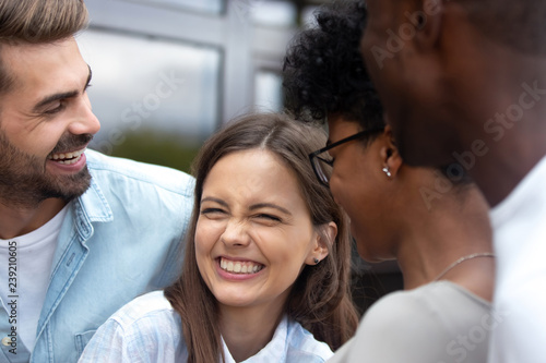 Canvas Print Young happy woman laughing at joke with multiethnic friends close up, African Am
