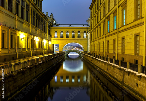 channel of the river leaving in an arch with reflection in water among walls of buildings on each side, St. Petersburg, Hermitage. The symmetry is vertical and horizontal.
