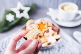 Christmas star in a woman's hand. Bowl with Christmas cookies on the wooden table