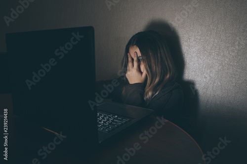 Teenager girl suffering internet cyber bullying scared and depressed cyberbullying. Image of despair girl humilated on internet by classmate. Young teenage girl crying in front of photo