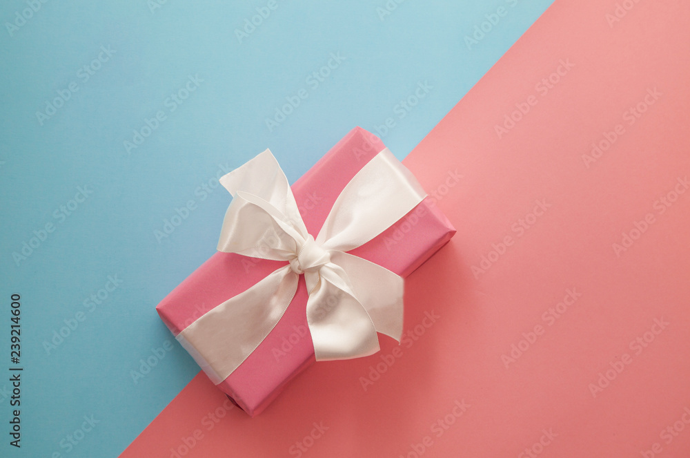 Festive pink and blue background. Gift with satin bow on coral background. Christmas. Wedding. Birthday. Happy woman's day. Mothers Day. Valentine's Day. Flat lay, top view. Festive pink and blue background. Gift with satin bow on coral background. Christmas. Wedding. Birthday. Happy woman's day. Mothers Day. Valentine's Day. Flat lay, top view.