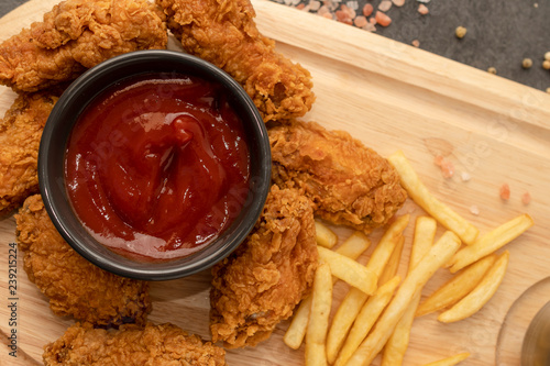 Chicken strips, french fries, and ketchup on a wooden tray. Fast food concept. 