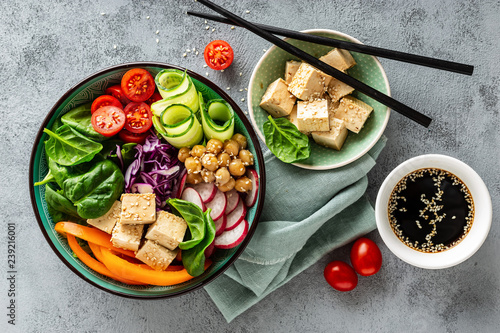 Buddha bowl salad with chickpeas, sweet pepper, tomato, cucumber, red cabbage kale, fresh radish, spinach leaves and tofu cheese, healthy balanced clean eating concept, top view, flat lay.