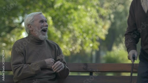 Funny old man saying goodbye to his friend with walking stick making butt prank