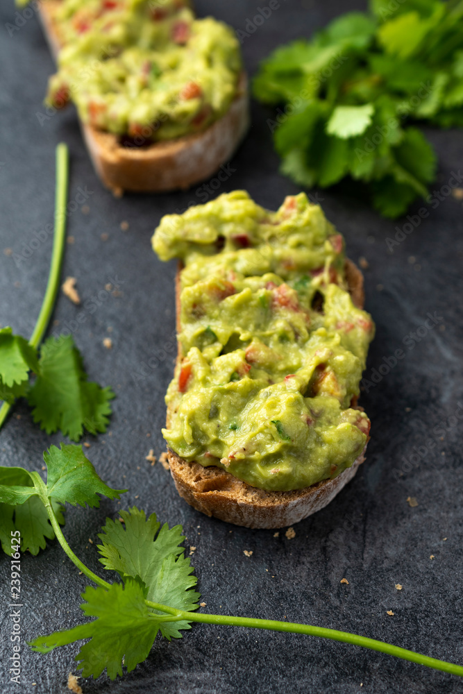 Fresh bread with Mexican homemade guacamole on a black table. Fresh bread with Mexican homemade guacamole on a black table.