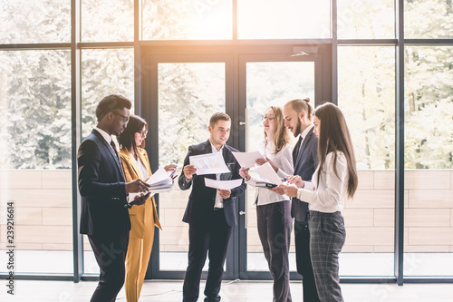 Business Corporate People Working Concept. Group of six young business people at the work meeting, holding financial reports and documents. Teamwork