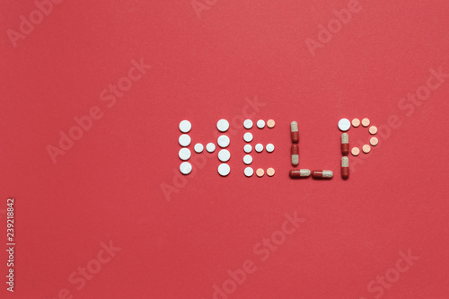 Pills scattered  on a red background. Inscription help