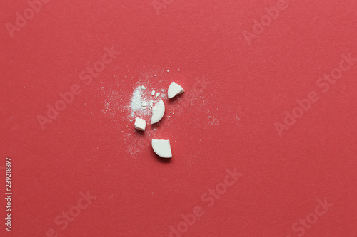White aspirin pill is split on red background
