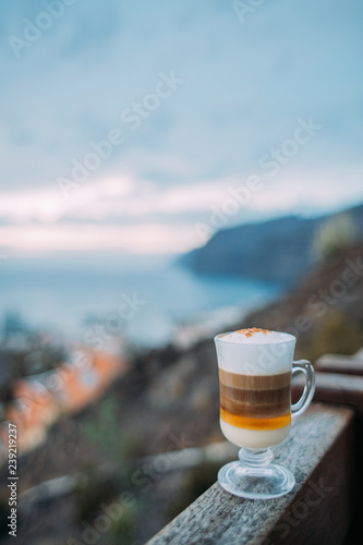 Barraquito, traditional coffee variety of Tenerife on background of ocean and harbor Los Gigantes, Canary Islands, Spain photo