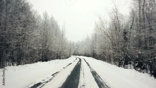 Driving through the winter forest on snowy road, first view. Camera outside the window on steadicam. Winter rural road landscape