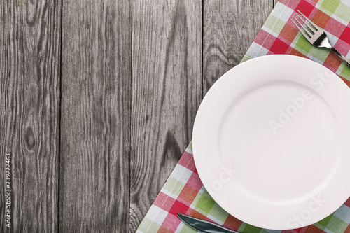 Cutlery and an empty white plate on the right side of the wooden table with copy space. Food background
