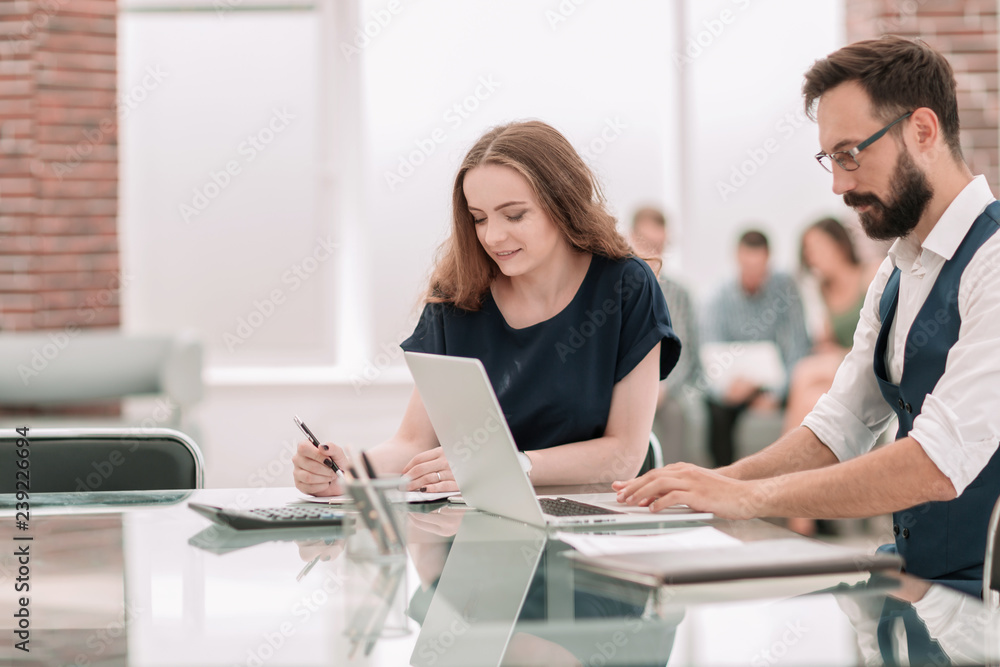 two employees sitting at a Desk in the office. two employees sitting at a Desk in the office.