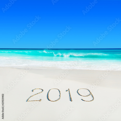 Perect white sandy ocean beach and season 2019 handwritten caption on sand