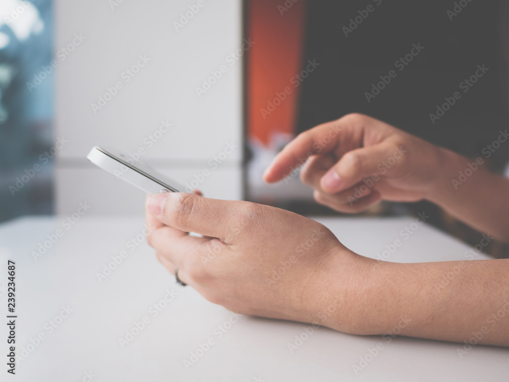 Woman hand holding and touching white mobile phone. She using application typing text message on smartphone