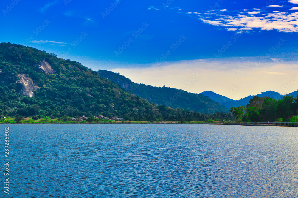 See in Thailand bei blauem Himmel und Bergen im Hintergrund