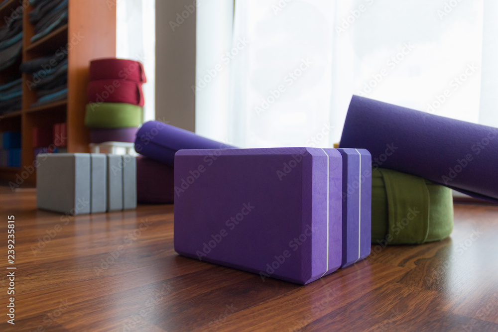 Set of yoga props wooden floor in studio. Set of blocks, meditation  cushions, mats and wood shelves stand with blankets on background. Iyengar  class accessories, wellness, workout activity concepts Stock Photo