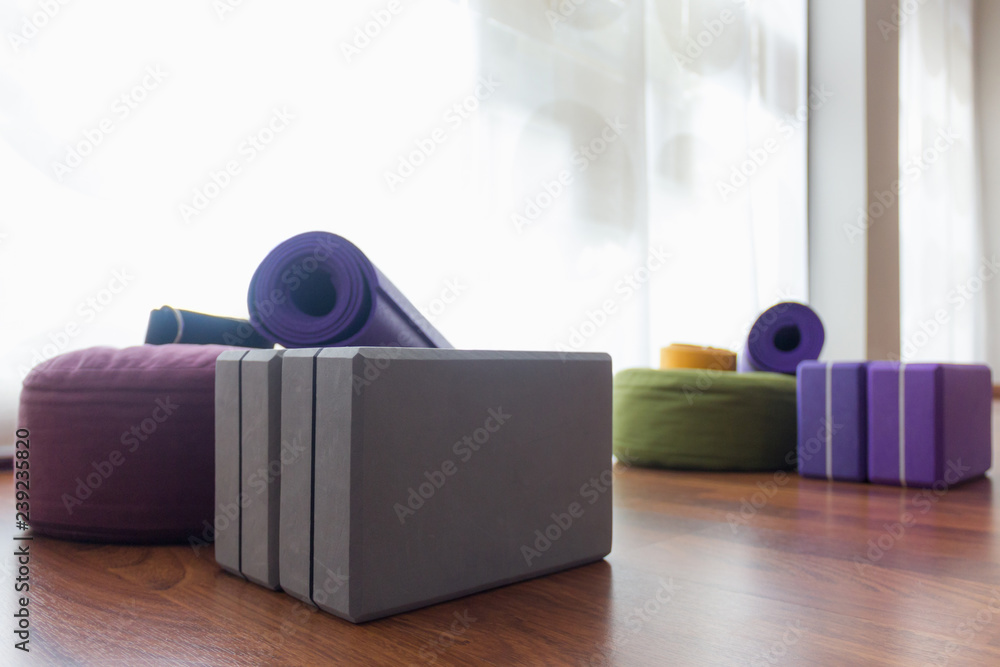 Variety of yoga props on studio wooden floor. Set of blocks, straps on  meditation cushions and mat. Iyengar class accessories, wellness, workout  activity concepts Stock Photo