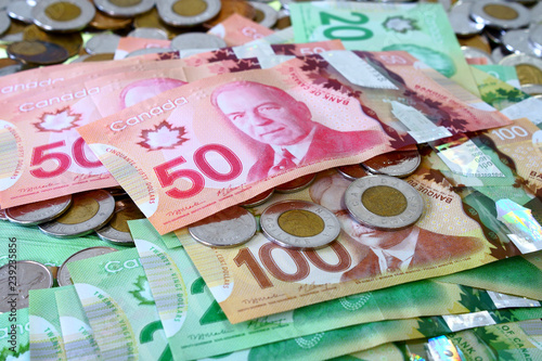 Many canadian dollar bills and spare change spread and filling the frame.