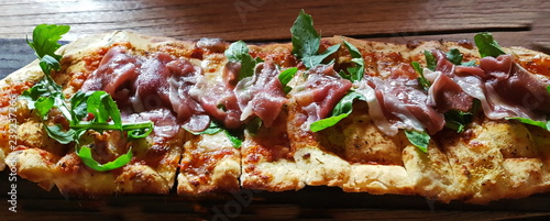  Flatbread with prosciutto cheese and arugula on wooden table.