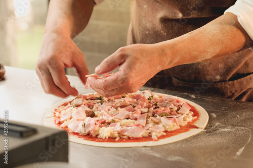 Closeup hand of chef baker in white uniform making pizza at kitchen. soft focus