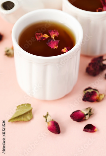 Herbal tea with roses on pink background