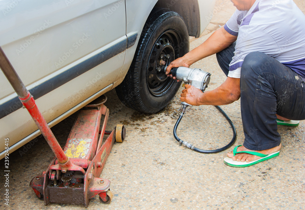 Fototapeta premium auto mechanic man change car wheel at maintenance shop,mechanician changing car tire in auto repair shop