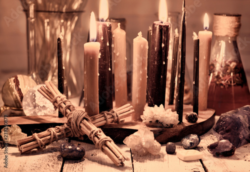 Vintage still life with cross, black candles, minerals and flasks on table. Magic ritual. Wicca, esoteric and occult background with vintage witch objects