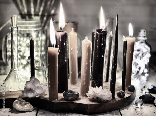Retro still life with burning black candles, shining bottles and minerals. Magic ritual. Wicca, esoteric and occult background with vintage witch objects photo