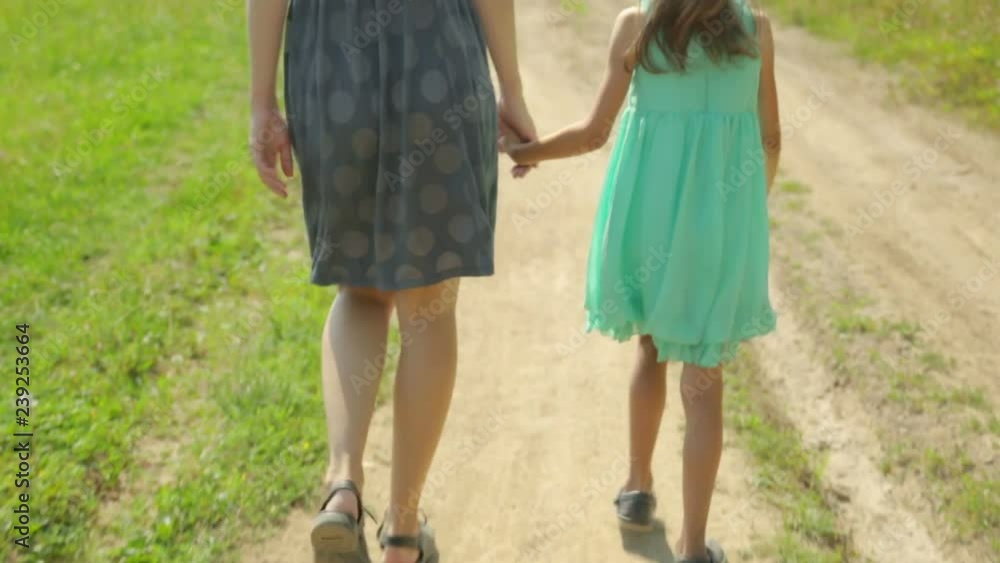 Mother and her daughter walking along a rural road Mother and her daughter walking along a rural road