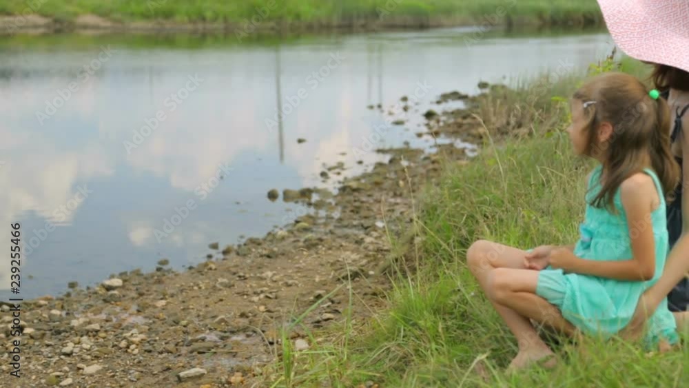 Mother and daughter resting on a river bank Mother and daughter resting on a river bank
