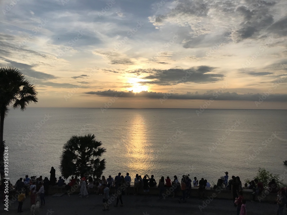 Sunset on the sea. Panoramic view from a viewpoint. Many people in foreground are looking on a sundown. Sky and beautiful clouds. Silhouettes of a crowd.