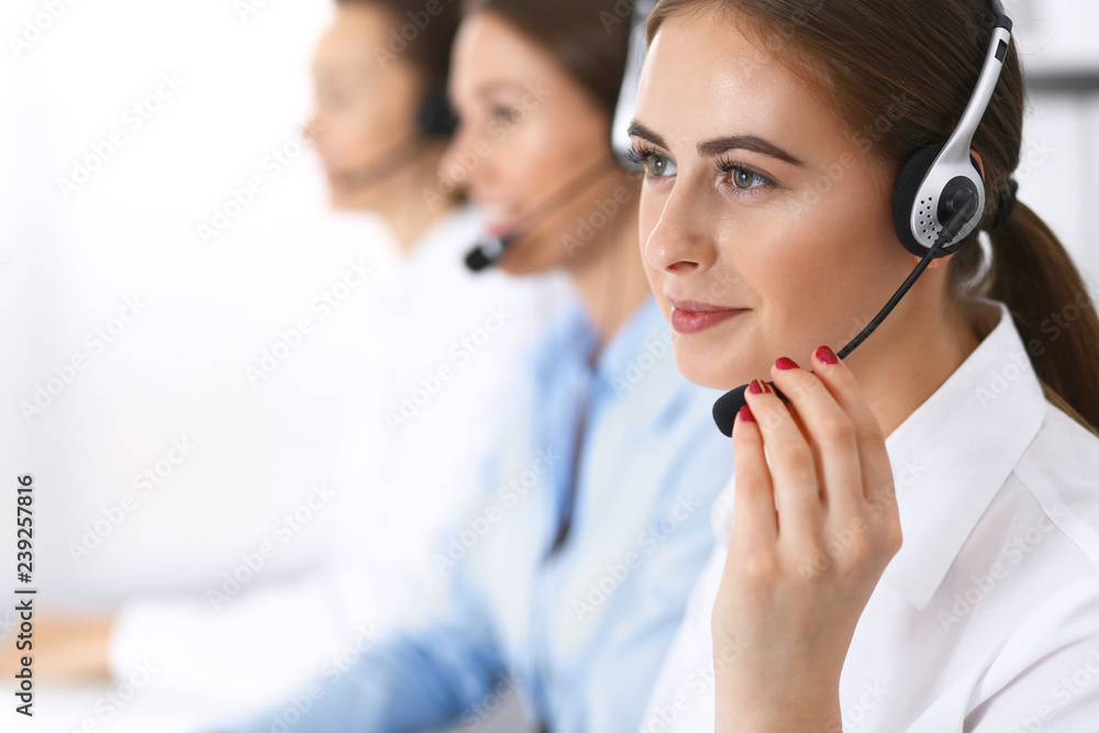 Call center. Group of operators at work. Focus at beautiful business woman in headset Call center. Group of operators at work. Focus at beautiful business woman in headset
