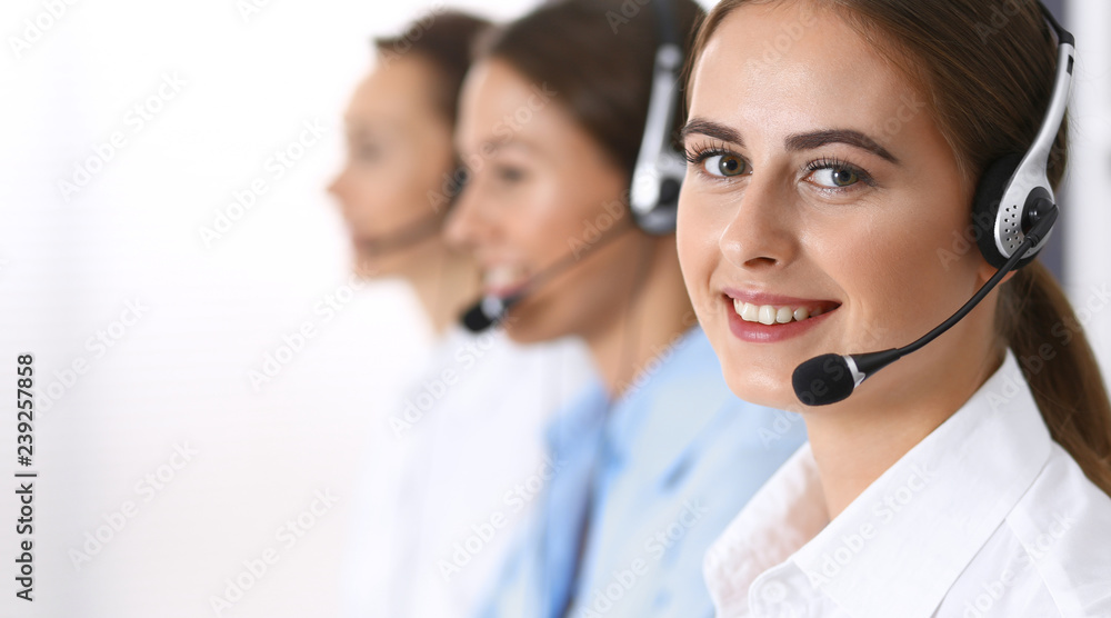 Call center. Group of operators at work. Focus at beautiful business woman in headset Call center. Group of operators at work. Focus at beautiful business woman in headset