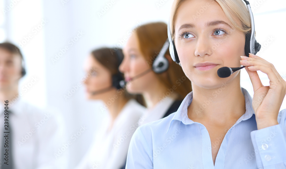 Call center. Group of operators at work. Focus at blonde business woman in headset Call center. Group of operators at work. Focus at blonde business woman in headset