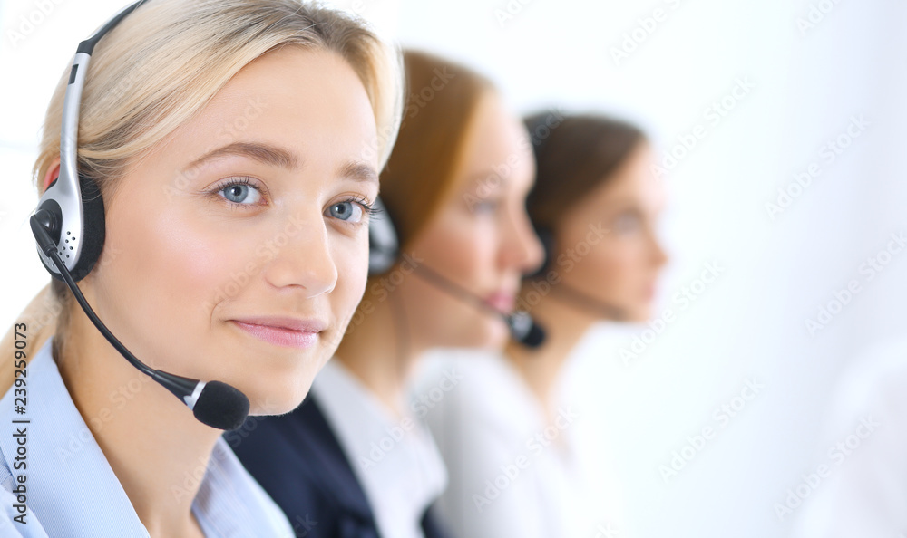 Call center. Group of operators at work. Focus at blonde business woman in headset Call center. Group of operators at work. Focus at blonde business woman in headset